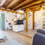 Spacious living room with exposed wooden beams and modern spiral staircase in Vrbanj stone house with pool.
