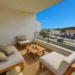 Covered balcony with lounge seating and distant sea view from a Hvar apartment.