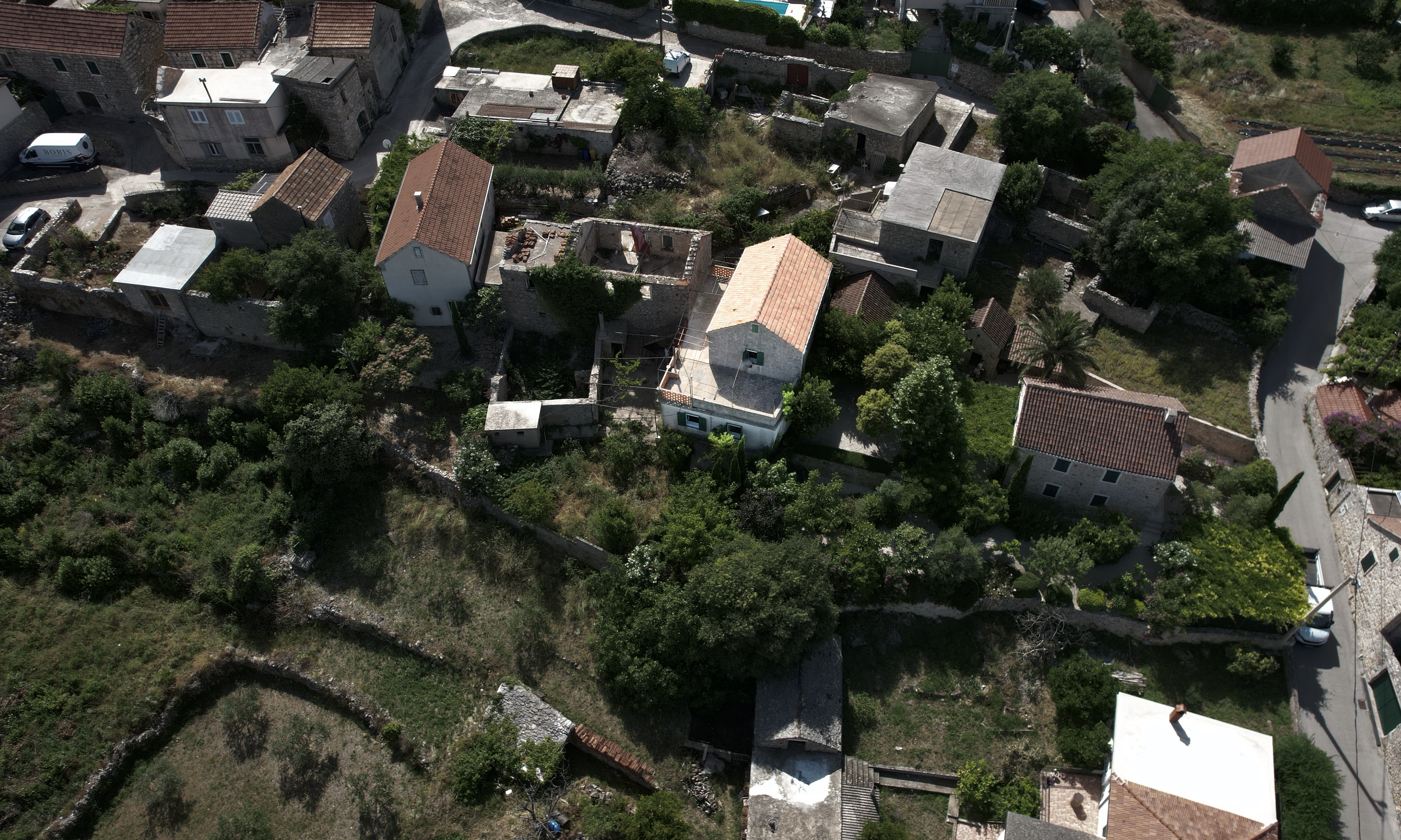 Aerial view of the stone house plot in Vrbanj with surrounding village homes and garden areas.