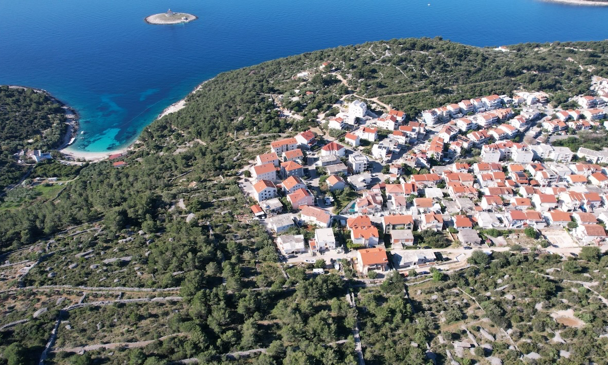 Aerial view of a residential area on the southeast slopes of Hvar with coastline, sea and nearby islands visible.