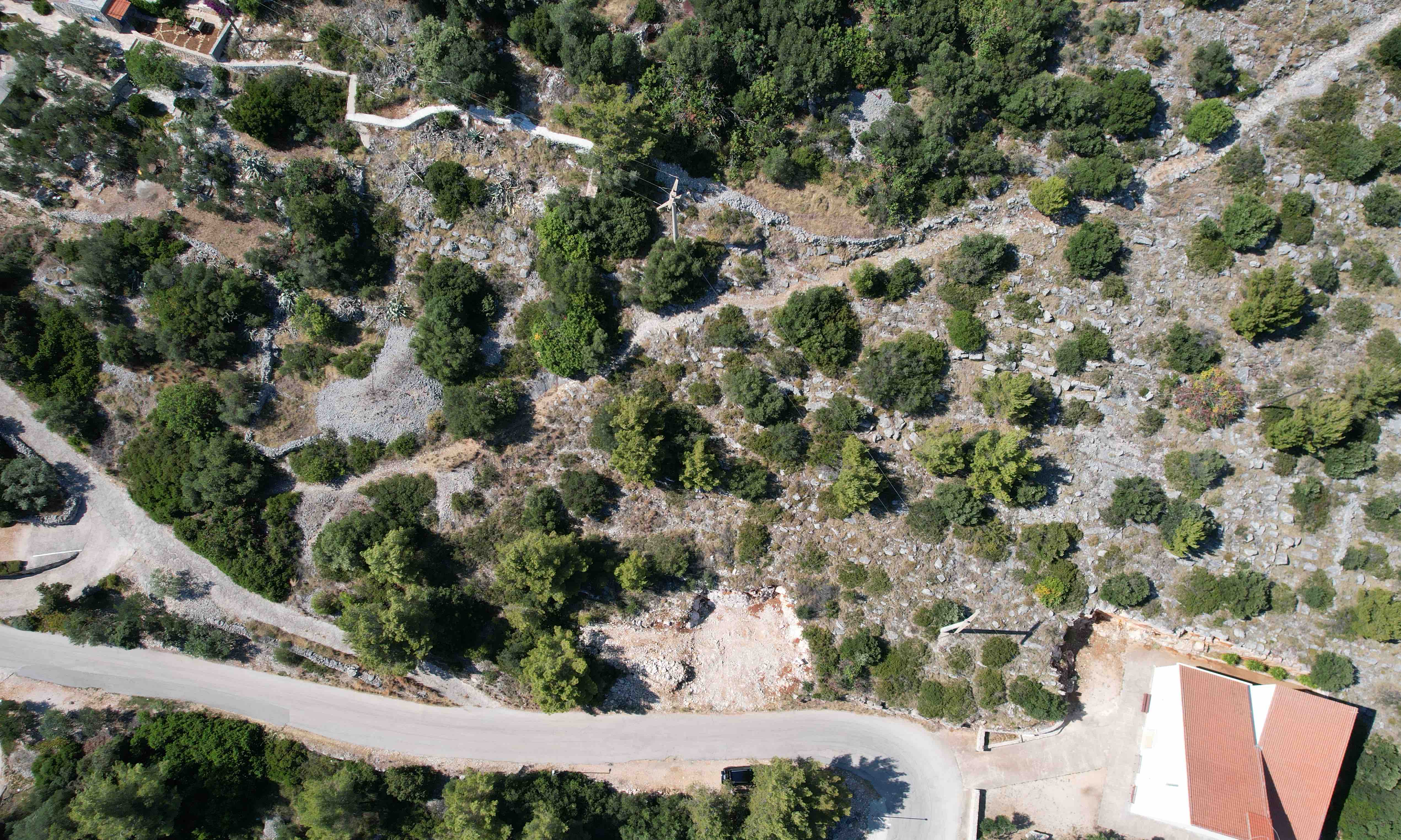Zavala building land Hvar drone view of sloping terrain, stone walls and Mediterranean vegetation near the road
